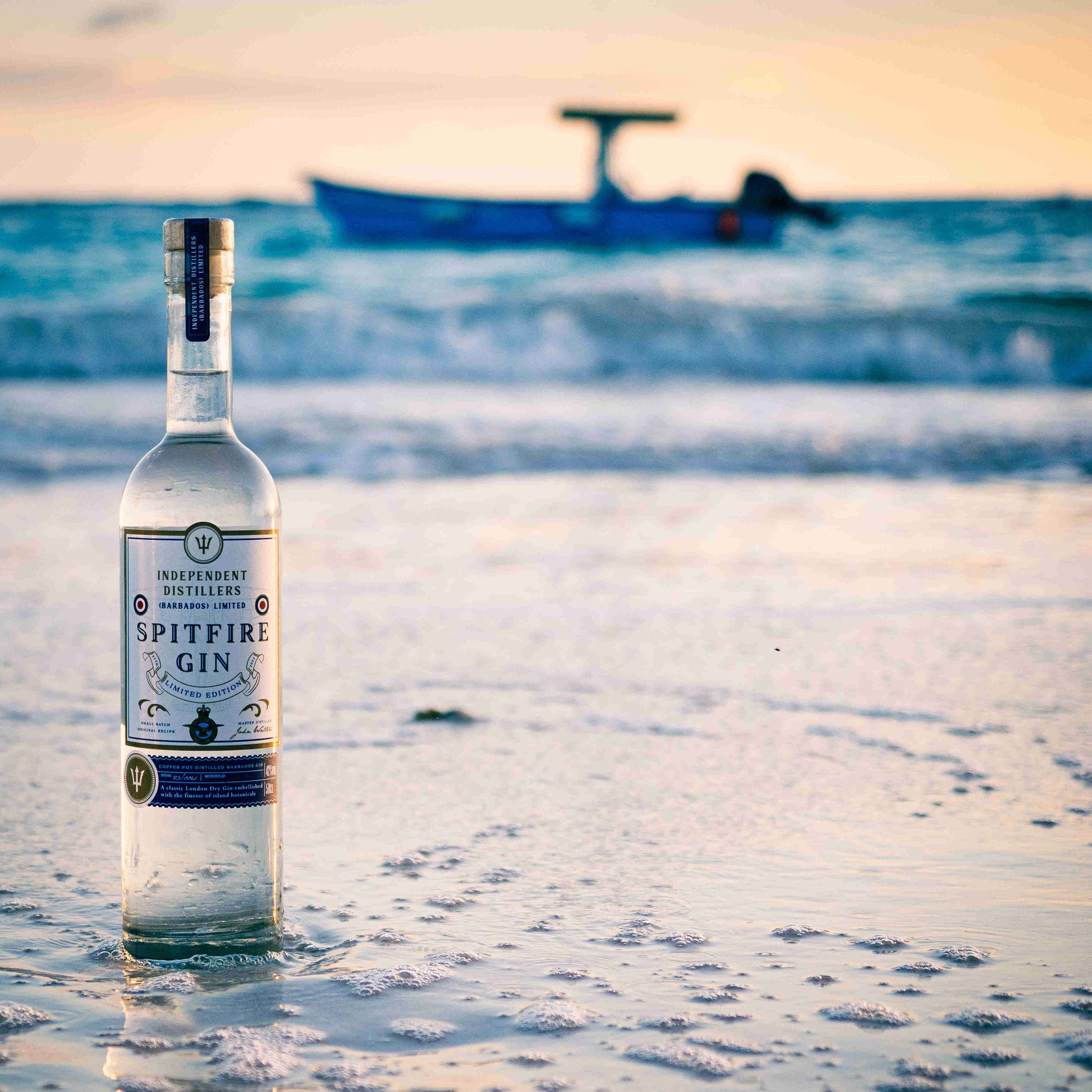 Barbados Spitfire Gin. 50cl bottle against blue Barbados waters. A crisp London Dry Gin that is silky smooth.